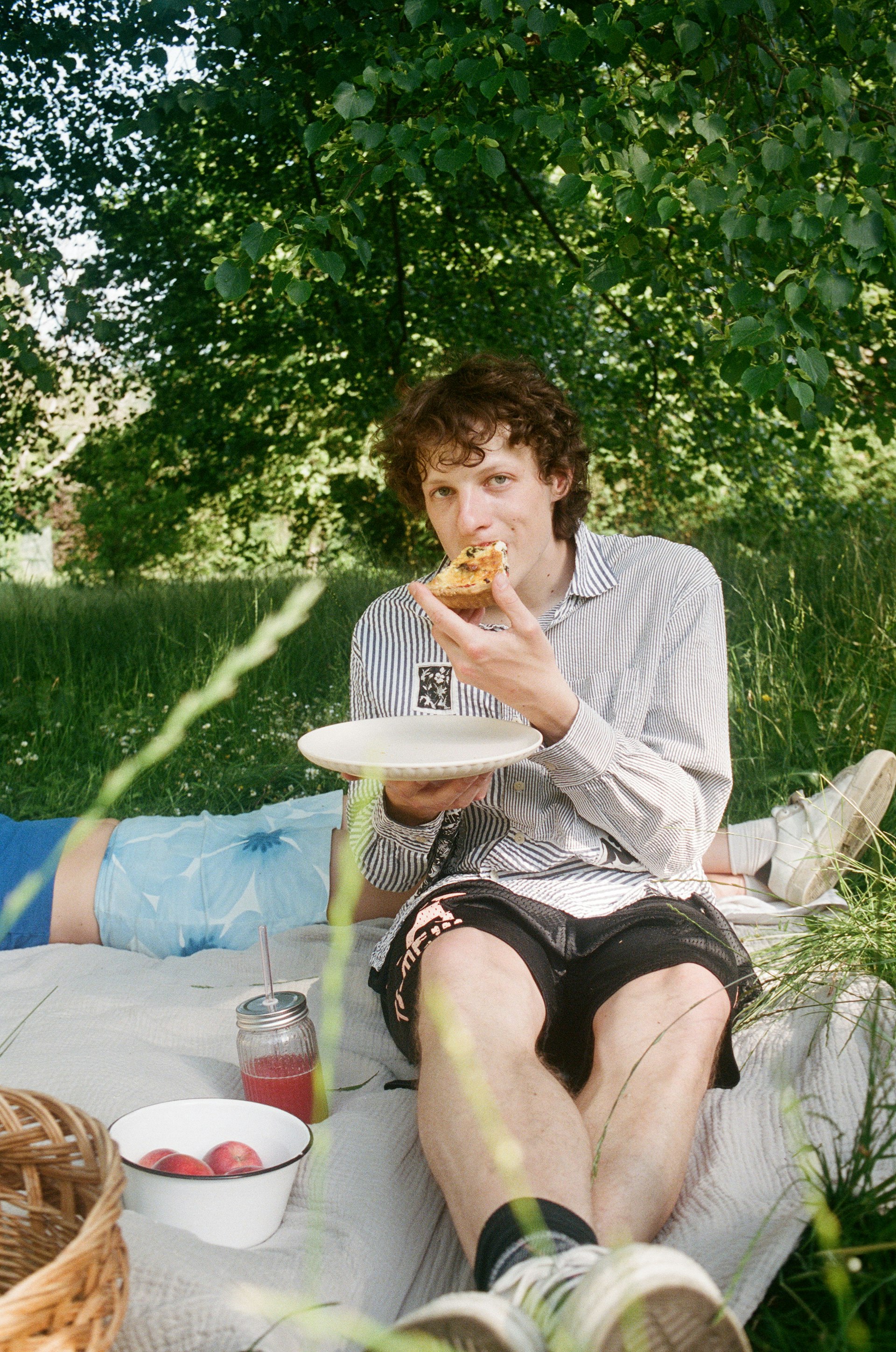 Mann isst Quiche auf Picknickdecke