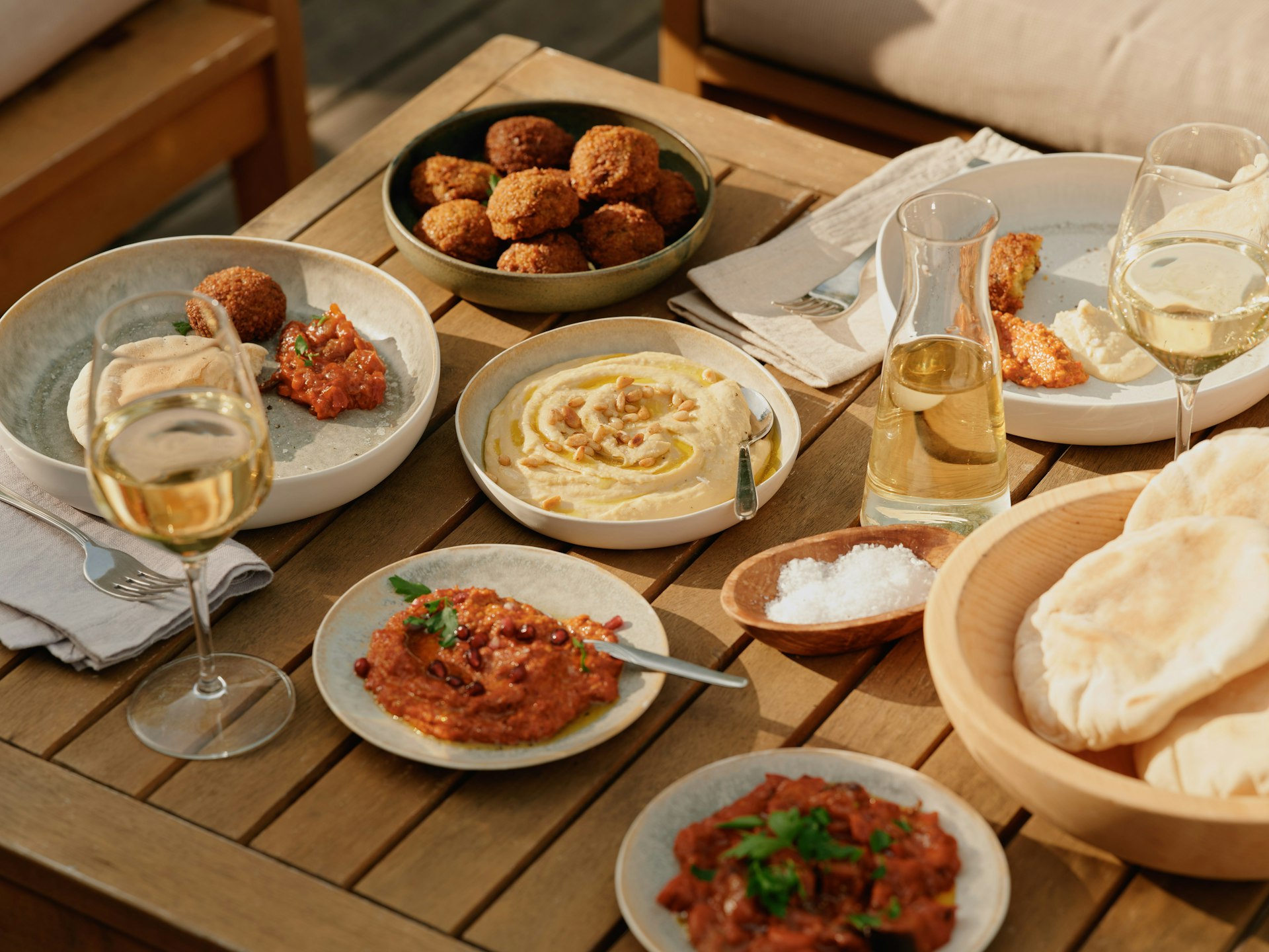 Tisch mit Weingläsern, Humus, Fladenbrot, Falafel und Muhammara